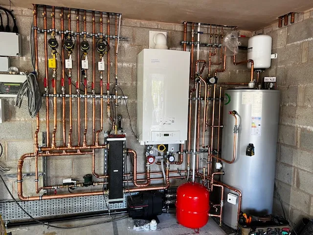 A room with a lot of pipes and a water heater.